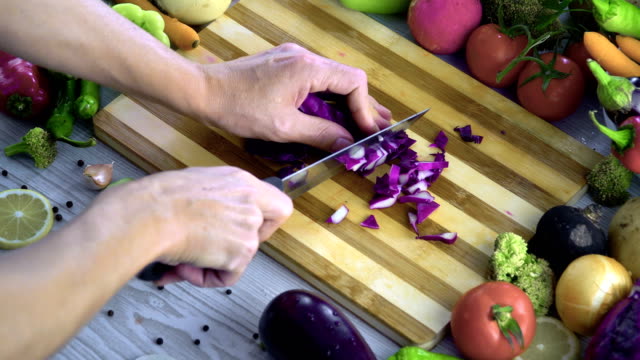 Man-is-cutting-vegetables-in-the-kitchen,-slicing-red-cabbage