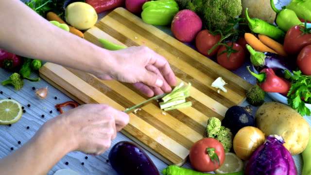 Man-is-cutting-vegetables-in-the-kitchen,-slicing-green-bell-pepper