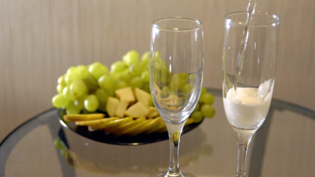 Cita-romántica.-Derramar-champán-en-copas-sobre-una-mesa-con-frutas