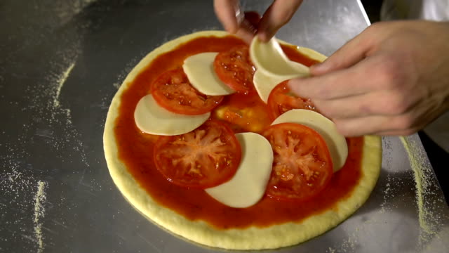 Chef-de-la-mano-pone-tomates-y-queso-en-primer-plano-de-la-pizza