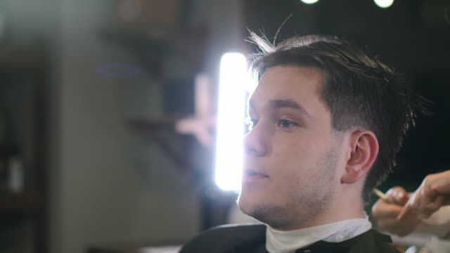 Hairdresser-cutting-hair-with-professional-scissors-and-comb-in-hairdressing-salon.-Close-up-haircutter-making-male-haircut-with-scissors-in-hairdressing-school