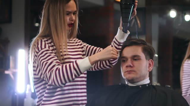 Barber-drying-male-hair-in-hairdressing-salon.-Close-up-hairdresser-blowing-man-hair-with-dryer-in-barbershop.-Male-hairstylish-doing-hairdo-in-beauty-studio