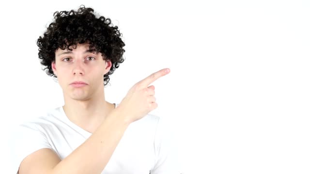 Pointing-on-Side,-Young-Man-with-Curly-Hairs,-white-Background