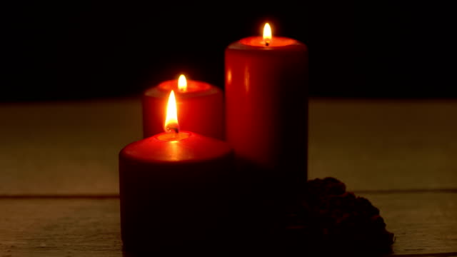 Combustión-de-tres-velas-rojas-y-rosas-en-tiempo-romántico-en-mesa-de-madera