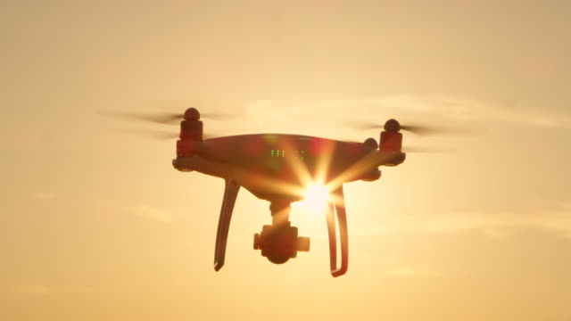 SLOW-MOTION-CLOSE-UP-SILHOUETTE-Filming-Drohne-mit-Kamera-überfliegt-der-aufgehenden-Sonne