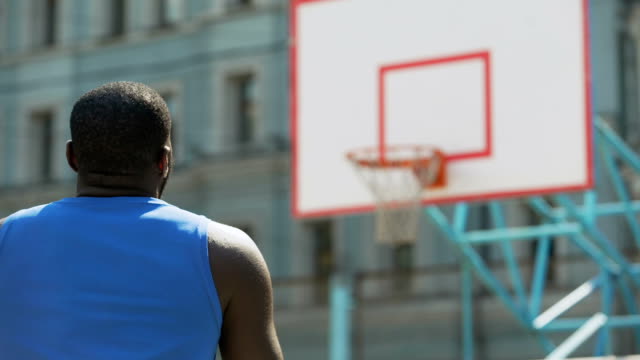Back-view-of-basketball-player-practicing-free-throws-outdoors,-active-lifestyle