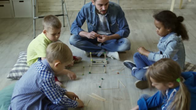 Kids-and-Male-Teacher-Making-Wooden-3D-Shapes
