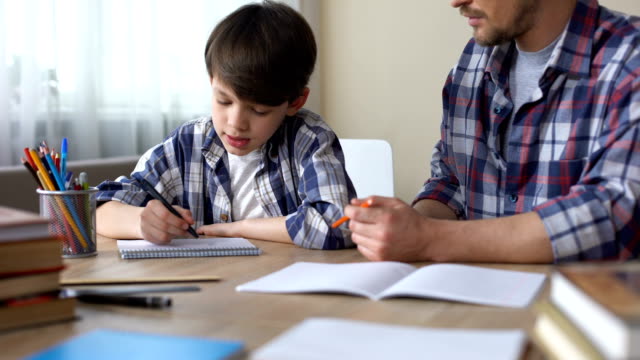 Vater-und-Sohn-gemeinsam-Hausaufgaben-Vater-erklären,-Aufgabe,-Schulbildung