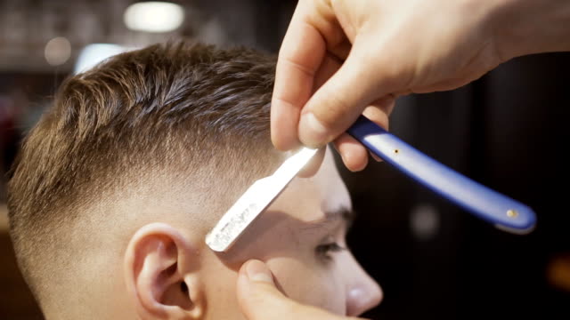 Hairstylist-makes-contour-to-hairstyle-with-sharp-blade