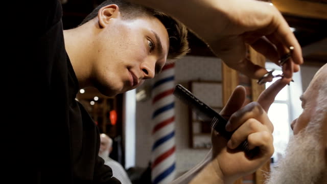 Professional-barber-cuts-brow-of-mature-man
