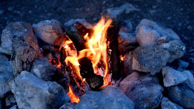 Lagerfeuer-in-ein-Lagerfeuer-von-Steinen-im-freien-in-der-Abenddämmerung
