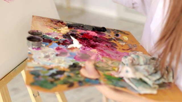 Artista-mezcla-pinturas-al-óleo-en-una-paleta-con-un-cepillo.