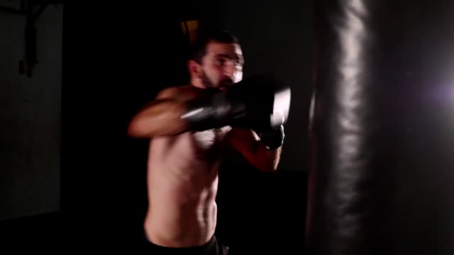 Boxer-hombre-haciendo-huelgas-en-una-bolsa-de-boxeo.-Combatiente-de-la-formación-interior