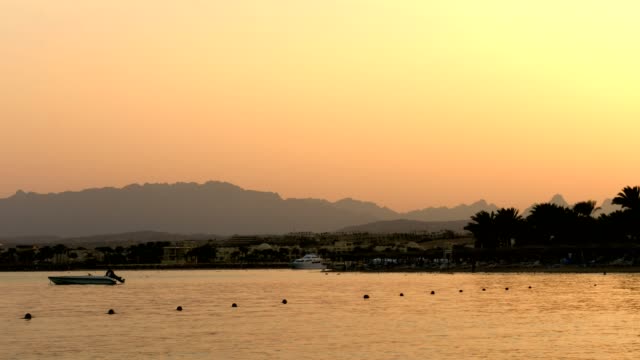 HURGHADA,-Ägypten---24.-Oktober-2018:-Einer-der-vielen-ruhigen-Buchten-des-Roten-Meeres,-bei-Sonnenuntergang,-in-der-Dämmerung.-vor-dem-Hintergrund-der-die-Umrisse-der-Berge-Palmen