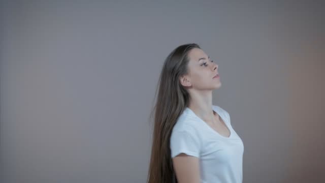 Eine-junge-Sport-Modell-zeigt-ihre-langen-Haare,-ich-bin-im-Studio-auf-einem-grauen-Hintergrund.-Slow-motion