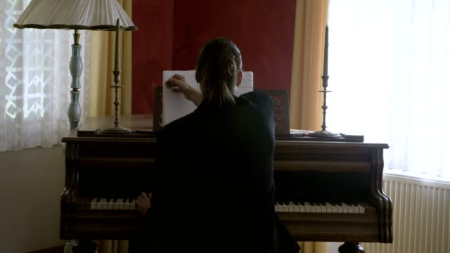 Long-hair-musician-reading-music-sheet-and-playing-piano