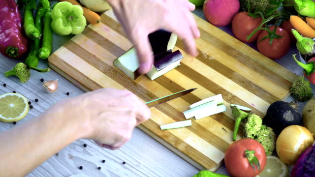 Man-is-cutting-vegetables-in-the-kitchen,-slicing-eggplant