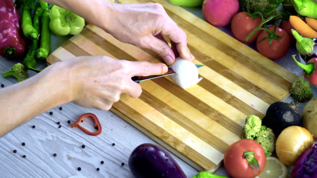 Man-is-cutting-vegetables-in-the-kitchen,-slicing-onion