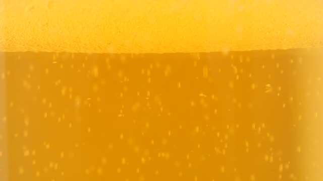 Slow-tilting-on-glass-full-of-beer-bubbles-and-foam-4K-2160p-UltraHD-footage---Golden-color-of-fresh-beer-bubbles-4K-3840X2160-UHd-video