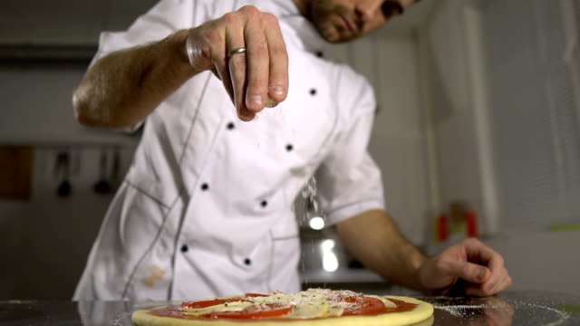 El-chef-rocía-especias-a-la-pizza-acabada-en-la-cocina