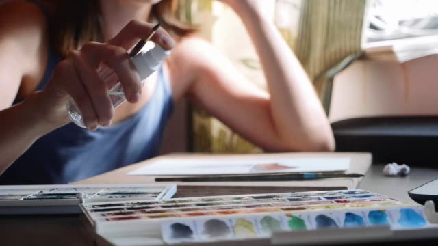 A-young-woman-moisturizes-the-paint-before-painting-with-watercolor,-slow-motion