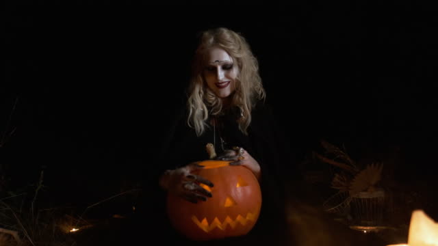 Halloween-Image-.Young-Witch-In-Black-Clothes-Holds-Pumpkin-In-Her-Hands.