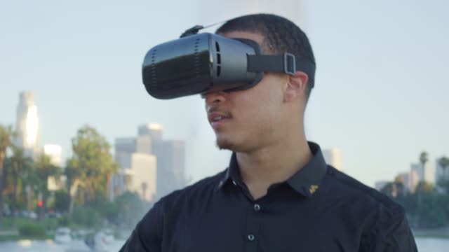 Junge-afrikanische-amerikanische-Mann-trägt-VR-Brille,-wie-er-in-einem-Park-spielt