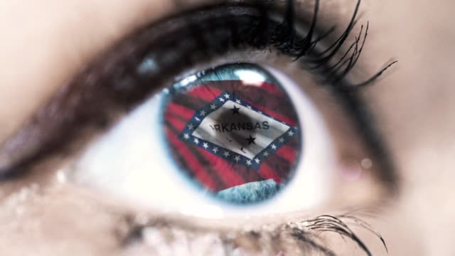 Mujer-ojo-azul-en-primer-plano-con-la-bandera-del-estado-de-Arkansas-en-iris,-estados-unidos-de-América-con-movimiento-de-viento.-concepto-de-vídeo