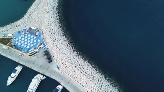vista-superior-en-hermoso-muelle-blanco-con-rocas-blancas-y-un-yates-sobre-fondo-de-agua-azul,-Limassol,-Chipre