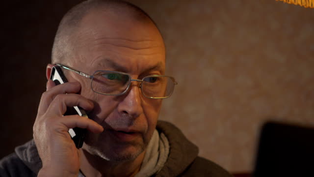 älterer-Mann-mit-einem-Laptop-und-am-Telefon-sprechen