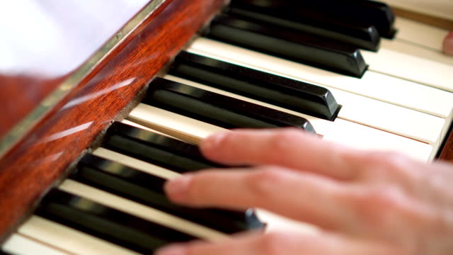Female-fingers-playing-keys-on-retro-piano-keyboard.-Shallow-depth-of-field.-Focus-on-piano-keys