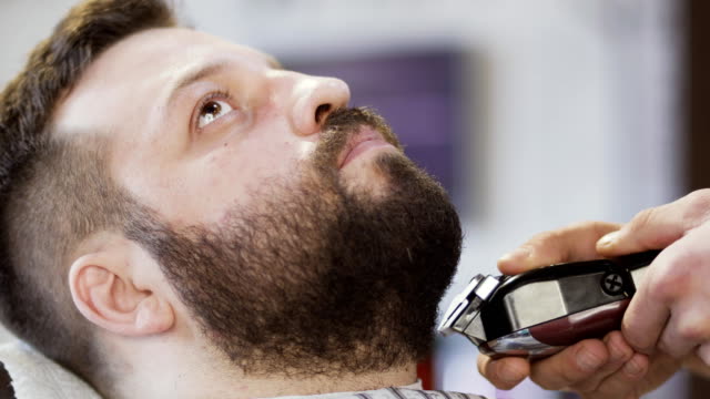 Barber-cuts-beard-of-customer-in-barbershop