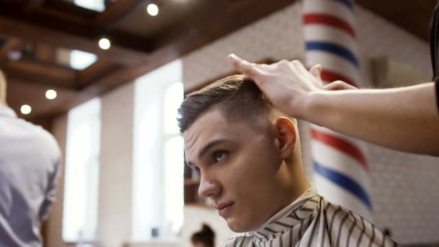 Professionelle-Friseur-macht-Frisur-mit-einem-jungen-Mann