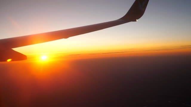Vista-desde-la-ventana-de-avión-a-hermoso-amanecer-o-atardecer.-Ala-de-avión-y-nubes-en-el-cielo.-Concepto-de-viaje-o-turismo.-Vista-de-cerca
