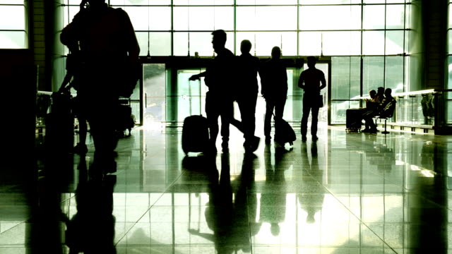 Silueta-de-pasajero-con-maleta-caminando-por-el-pasillo-en-el-aeropuerto