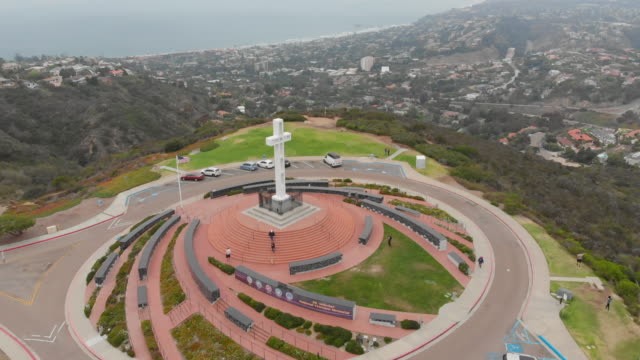 Statische-Luftaufnahme-des-Mount-Soledad-in-San-Diego,-Kalifornien-mit-Kreuz,-Autos,-Fußgänger,-Bäume,-Rasen,-Heime-und-Küste-in-Sicht.