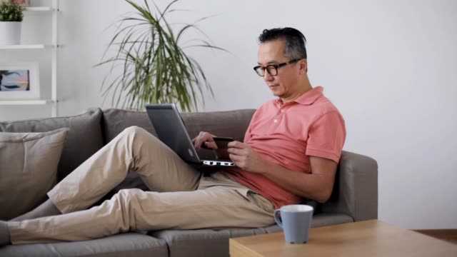 Mann-mit-Laptop-und-Kreditkarte-zu-Hause-auf-sofa