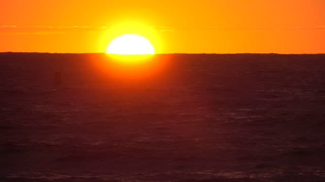 SLOW-MOTION-Bright-orange-Sonnenuntergang-hinter-dem-endlosen-blauen-Meer-an-einem-Sommertag