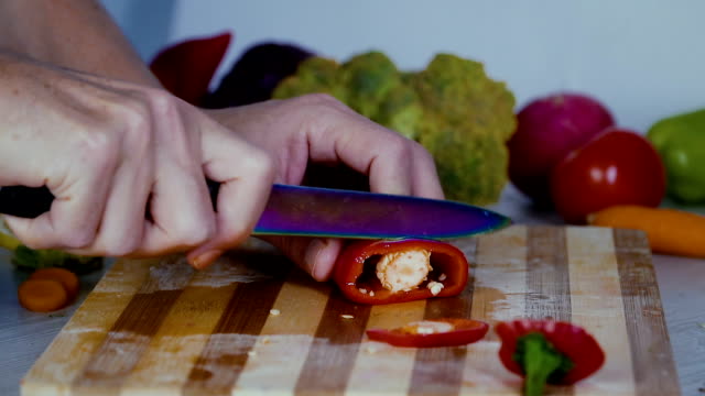 Man-is-cutting-vegetables-in-the-kitchen,-slicing-red-bell-pepper-in-slow-motion