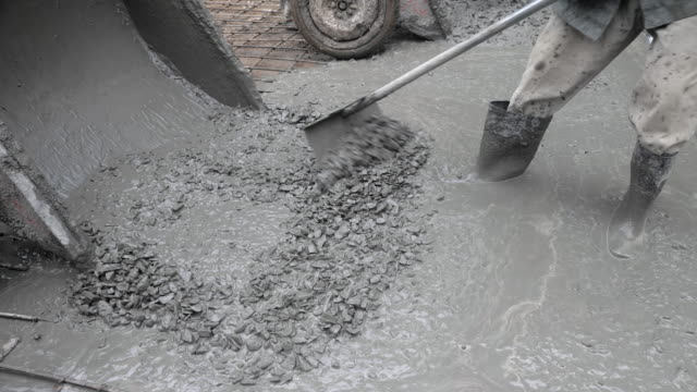 close-up-of-construction-workers-pouring-cement-on-a-rural-road