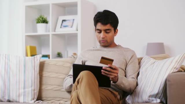 Mann-mit-TabletPC-und-Kreditkarte-zu-Hause-auf-sofa