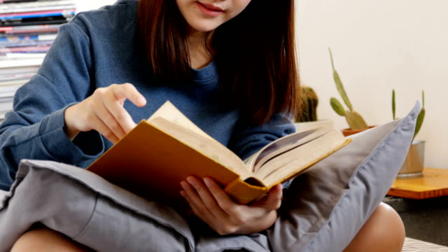 Attractive-asian-woman-reading-book-at-her-room.-People-with-education-concept.