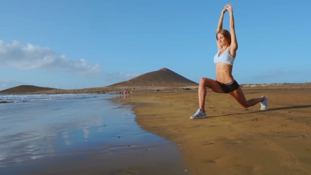 Mujer-haciendo-la-pierna-se-extiende.-Chica-fitness-estirando-las-piernas-en-el-entrenamiento-de-la-playa.-CÁMARA-LENTA-STEADICAM