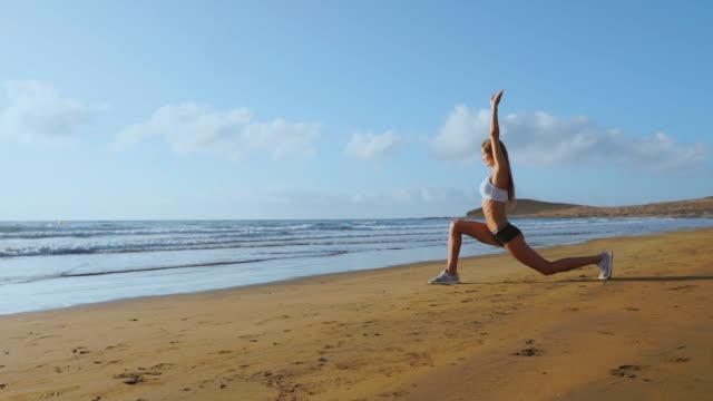 Woman-doing-leg-stretches.-Fitness-girl-stretching-legs-on-beach-training.-SLOW-MOTION-STEADICAM