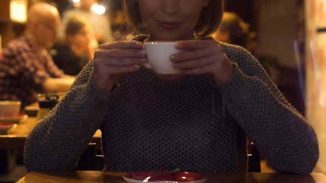 Pretty-young-woman-drinking-cappuccino-sitting-in-restaurant,-hot-beverage