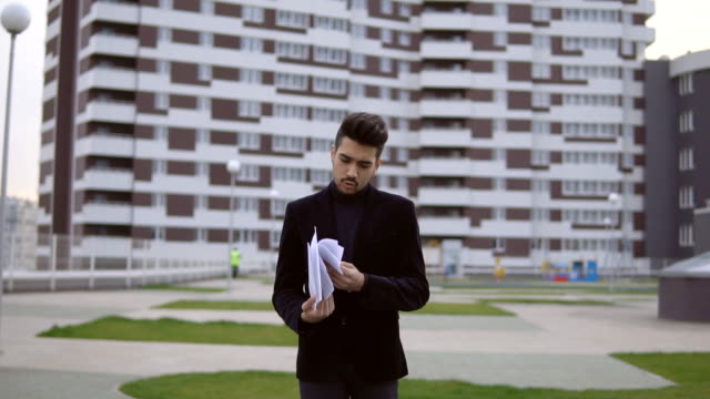 Attractive-young-businessman-in-black-suit-throw-out-documents-outdoor