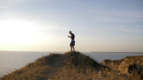 outdoor-sports,-strong-fighter-men-perform-boxer-strikes-before-contest-on-workout-on-hill-on-nature-near-water