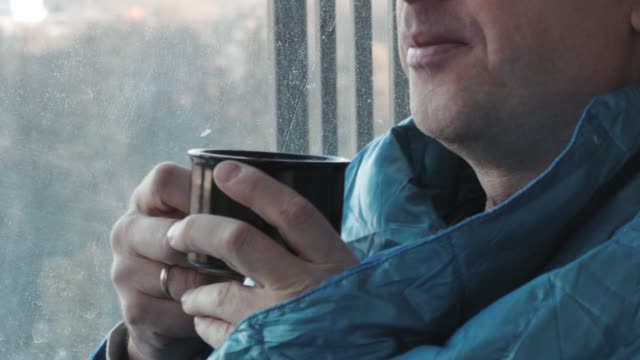 Man-drinking-coffee-in-the-morning-in-the-kitchen-at-home-close-up.-He-froze-and-wrapped-in-a-blanket.