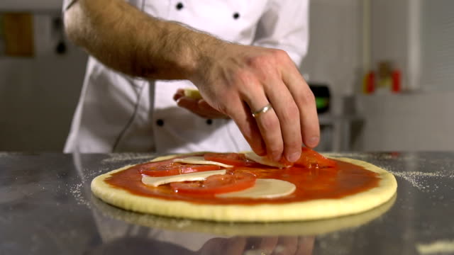 Hand-Chef-legt-Tomaten-und-Käse-in-der-Pizza-Nahaufnahme