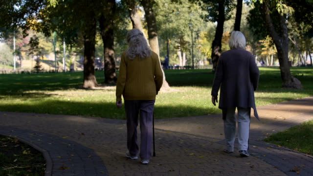 Two-old-ladies-enjoying-walk-in-park,-nursing-home-for-elderly-people,-leisure